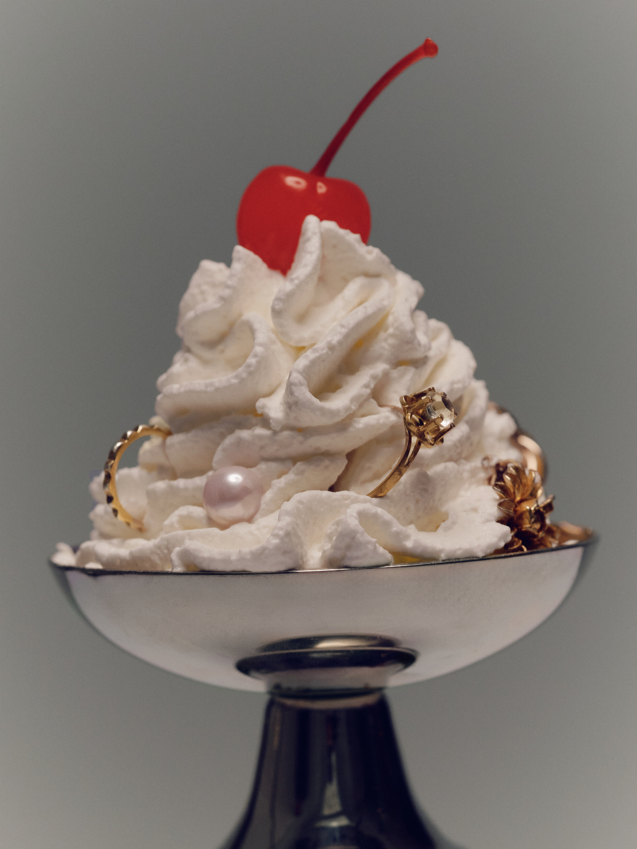 Silver coupe of cream set with gold rings and a cherry