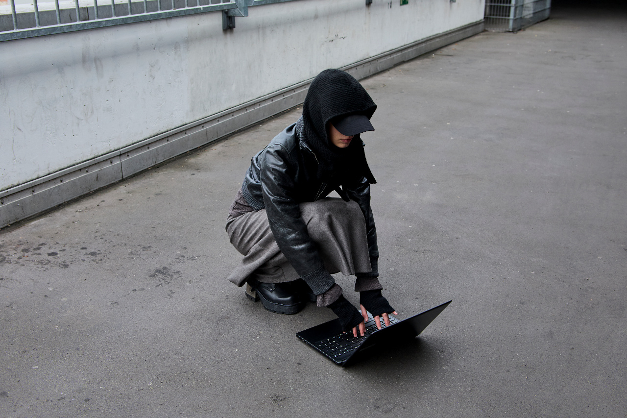 Figure crouched over a laptop on bare concrete