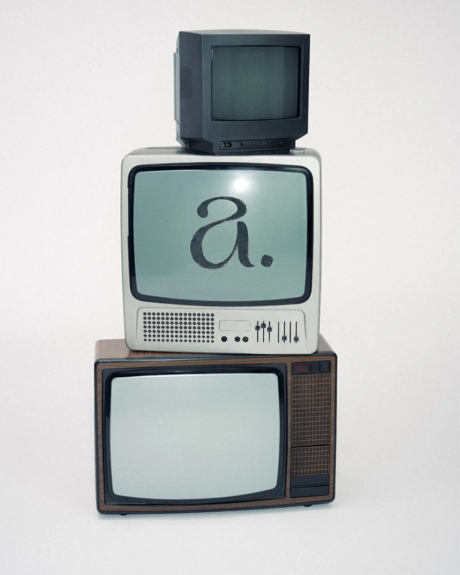 Stacked vintage televisions on a pale ground