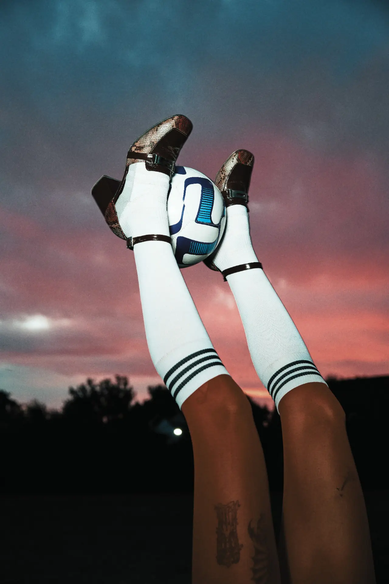Legs raised against a pink dusk sky holding a ball